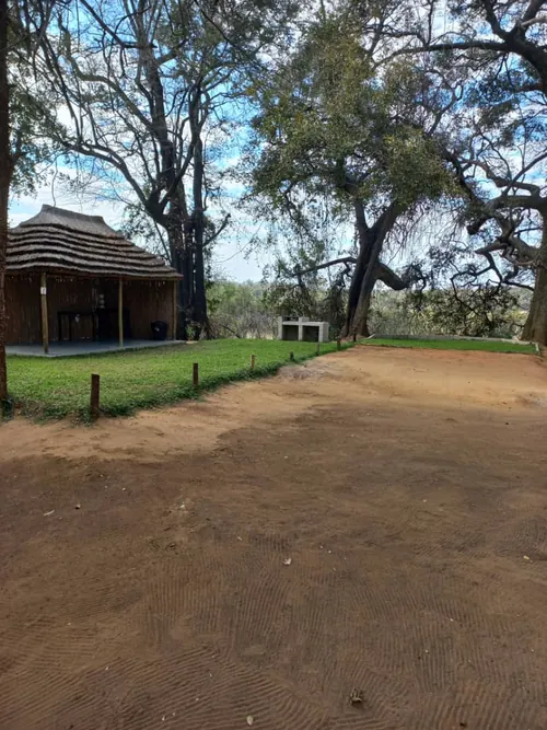 Campsite 7 with a thatched shelter under large trees